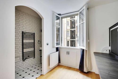 La salle de bains blanche est pourvue d'une fenêtre et d'une porte. dans l'établissement Magnificent Apartment 2 BDR-4P- Invalides, à Paris