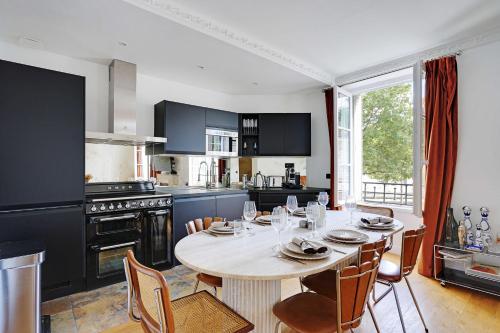 une cuisine avec une table blanche, des chaises et une table ainsi qu'une cuisine avec dans l'établissement Magnificent Apartment 2 BDR-4P- Invalides, à Paris