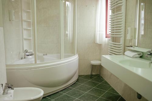 a white bathroom with a tub and a sink at Hotel Radobolja in Mostar