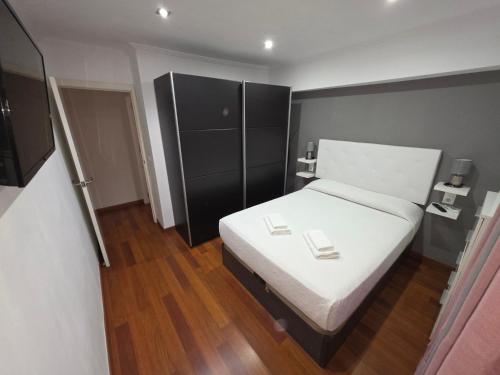 a bedroom with a white bed and a black cabinet at Magnífico alojamiento cerca de Mezquita catedral in Córdoba