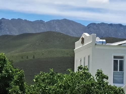 a white building with mountains in the background at Klaasvoogds Loft in Robertson