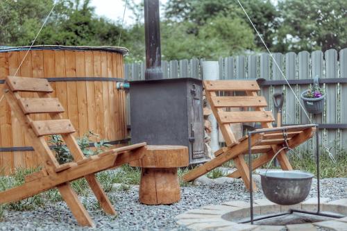 a wooden chair and a grill in a backyard at Woodlandia Resort Borjomi in Borjomi