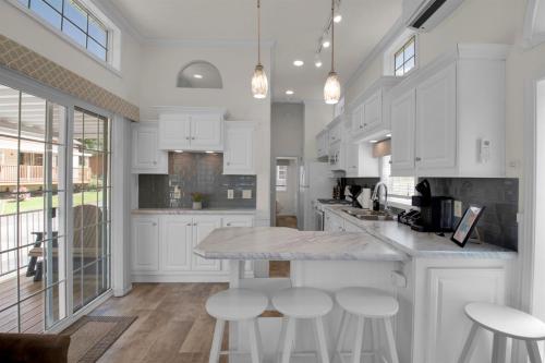 a kitchen with white cabinets and a island with stools at 1BR Model Home with Loft in Pigeon Forge