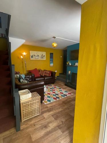 a living room with yellow walls and a couch at The Bolthole in Nailsworth