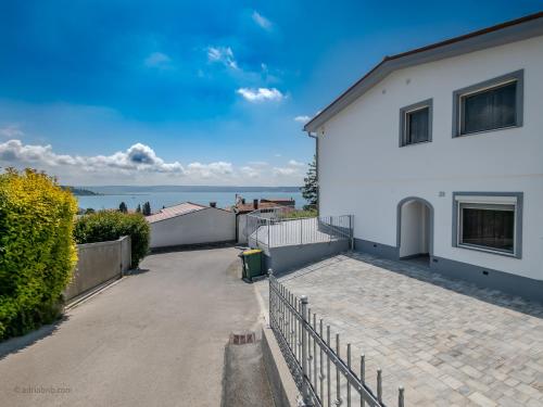 a white house with a driveway and the ocean in the background at Elegant Apartments BOP in Portorož