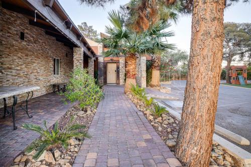 a brick sidewalk next to a building with a tree at 1-Acre Las Vegas Getaway Pool, Spa and Tennis Court in Las Vegas