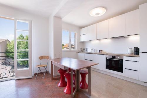 une cuisine avec une table en bois et des tabourets rouges dans l'établissement L'Elegant l Bright & Views l Shellter Rentals, à Saint-Tropez