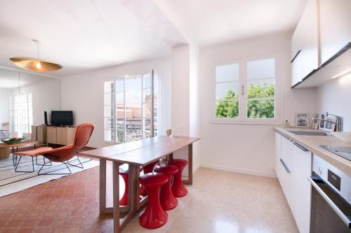 une cuisine avec une table en bois et des tabourets rouges dans l'établissement L'Elegant l Bright & Views l Shellter Rentals, à Saint-Tropez