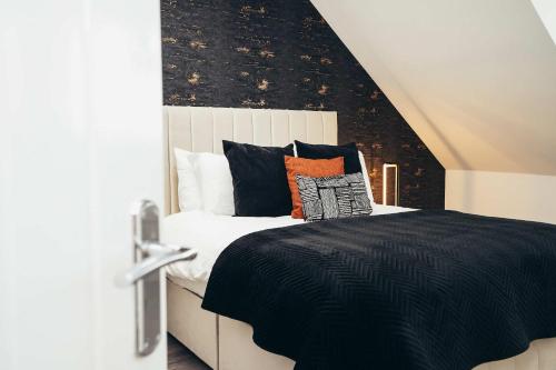 ein Schlafzimmer mit einem schwarz-weißen Bett mit Kissen in der Unterkunft Hen & Chickens Luxury Apartments, Free Parking, By DerBnB in Derby