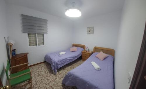 two beds in a room with purple sheets at Casa amaro in Vejer de la Frontera