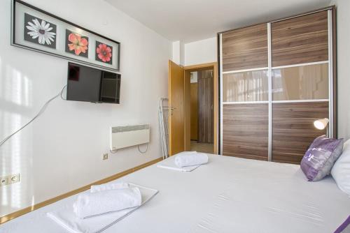 a bedroom with a white bed and a tv on the wall at Mountain view apartment in Aspen Golf Resort with SPA in Bansko