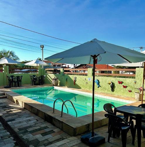 a pool with an umbrella and a table and chairs at Pousada Aconchego de Maricá in Maricá