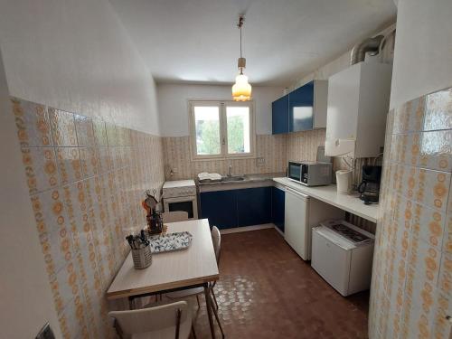 une cuisine avec des placards bleus et une table avec des chaises dans l'établissement Studio RDC 4 pers, accès direct plage, terrasse vue mer - FR-1-776-55, à Argelès-sur-Mer