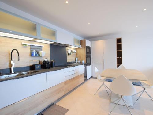 une cuisine avec des armoires blanches et une table et des chaises dans l'établissement Spacieux appartement 4 pers avec balcon, wifi et animaux admis - FR-1-498-101, à Évian-les-Bains