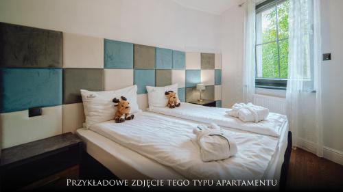 two teddy bears sitting on top of a bed at Norweska Dolina Family&Pet-friendly Resort in Szklarska Poręba