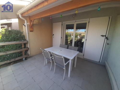 une table blanche et des chaises sur une terrasse dans l'établissement Charmant Pavillon 5 Pers avec Clim et Terrasse en Résidence avec Piscine - FR-1-781-85, à Vendres