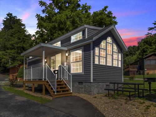 a black house with a porch and a bench in front of it at Lovely 1BR Cottage with Loft in Pigeon Forge