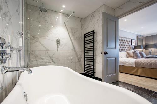 a bathroom with a tub and a shower and a bed at Freemasons at Wiswell in Whalley