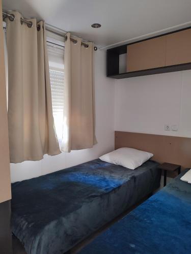 une chambre avec un lit et une fenêtre avec des rideaux dans l'établissement Camping DEL MAR 4 Étoiles à ARGELÈS SUR MER Mobil-Home Cosy en 3Ch au calme, à Argelès-sur-Mer