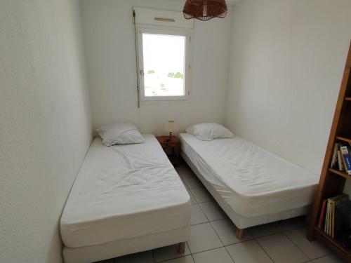 deux lits dans une petite pièce avec une fenêtre dans l'établissement Appart 2 ch avec loggia à 100m du centre - FR-1-781-89, à Valras-Plage