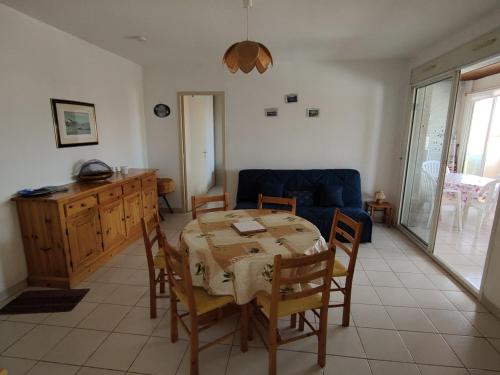 un salon avec une table et un canapé bleu dans l'établissement Appart 2 ch avec loggia à 100m du centre - FR-1-781-89, à Valras-Plage
