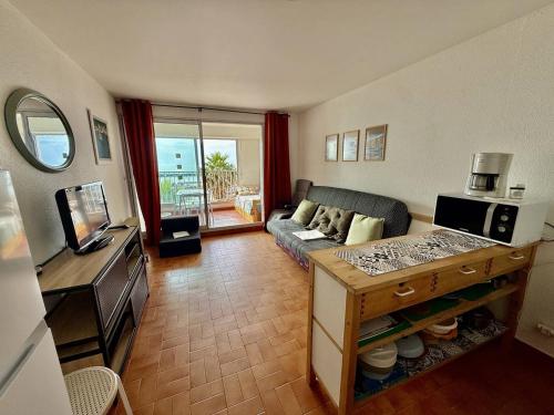 Il comprend un salon doté d'un canapé et d'une télévision. dans l'établissement Studio confortable au Cap d'Agde, proche plage, 4 pers - FR-1-723-46, au Cap d'Agde