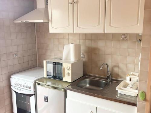 une cuisine avec un évier et un micro-ondes dans l'établissement Charmant F2 avec Loggia et Parking à 800m des Cures - 4 couchages - Amélie-les-Bains - FR-1-703-140, à Amélie-les-Bains-Palalda