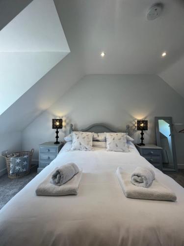 a bedroom with a large white bed with towels on it at Woodpecker Lodge in Frampton