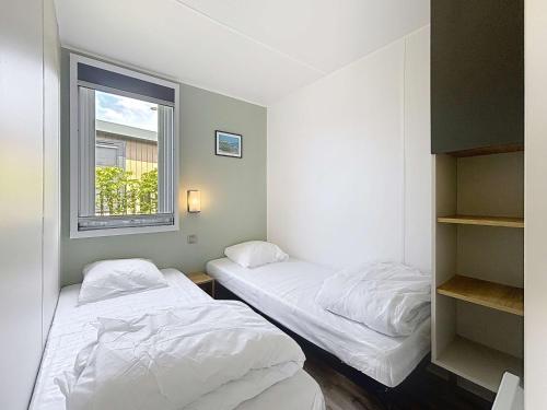 deux lits dans une chambre avec une fenêtre dans l'établissement Mobil-home Grand Confort 4 pers, 2 chambres, 1 sdb, clim, terrasse & parking, à 200m de la plage - FR-1-361A-2, à Jullouville