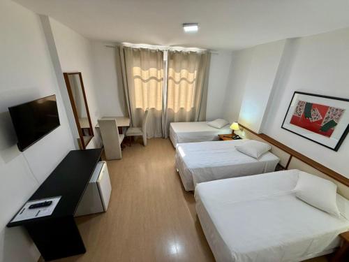 a hotel room with two beds and a television at César Park Hotel in Juiz de Fora