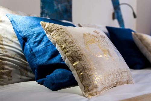 a white pillow on a bed with blue pillows at Mercatovecchio Luxury Suites in Udine