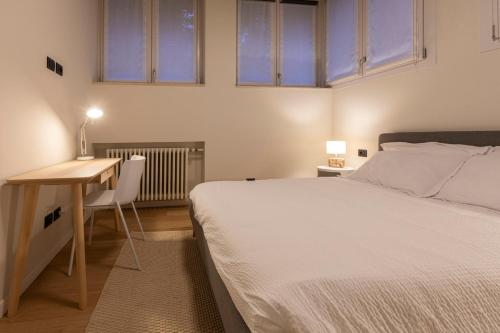 una camera da letto con un letto, una scrivania e due finestre di Grancini Suite a Milano