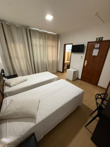 a hotel room with two beds and a television at César Park Hotel in Juiz de Fora