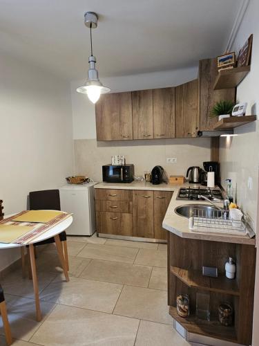 Una cocina con gabinetes de madera y un fregadero y una mesa. en Old Center ThaliaApartment, en Sibiu