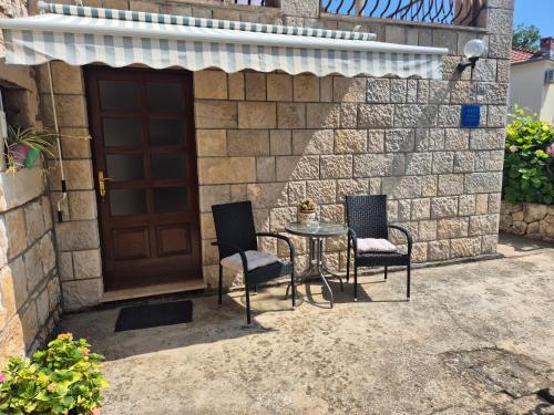 a patio with two chairs and a table in front of a door at Studio Airport Dubrovnik in Čilipi