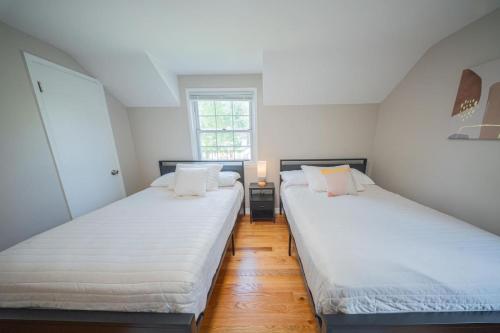 two beds in a room with white walls and wooden floors at Newly Renovated Townhouse on a Tranquil Street in Dearborn