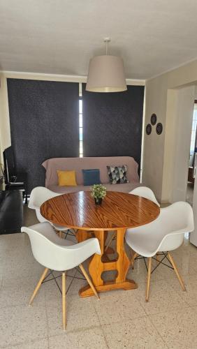 a living room with a wooden table and white chairs at Magic Sea Apartments in Larnaka