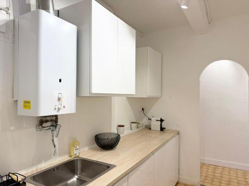 une cuisine avec des armoires blanches et un évier dans l'établissement Charmant 2 pièces proche mer, à Nice