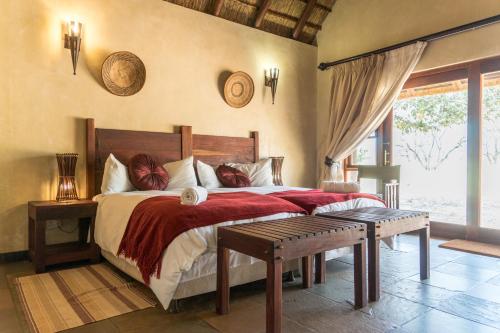 a bedroom with a large bed with a red blanket at Zebula Golf Estate & Spa Executive Holiday Homes in Mabula