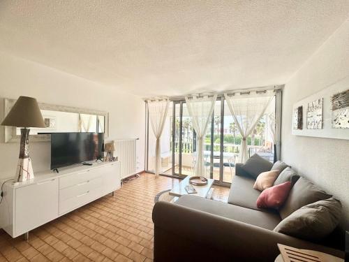 un salon avec un canapé et une télévision dans l'établissement Appartement - Cap d'Agde, au Cap d'Agde