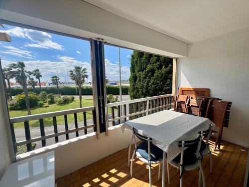 un balcon avec une table et des chaises et une grande fenêtre dans l'établissement Appartement - Cap d'Agde, au Cap d'Agde