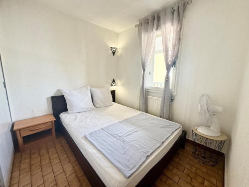 une petite chambre avec un lit et une fenêtre dans l'établissement Appartement - Cap d'Agde, au Cap d'Agde