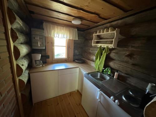 a kitchen in a log cabin with a sink and a window at Nivan Majoitus in Joensuu