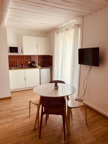- une cuisine avec une table, une table et des chaises dans l'établissement Le Nid des Salins - Studio Mer & Terrasse, à Hyères