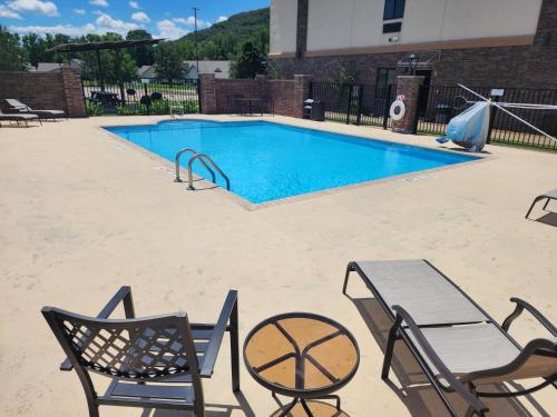 a swimming pool with two chairs and a table and a table and chairs at Holiday Inn Express and Suites Heber Springs by IHG in Heber Springs