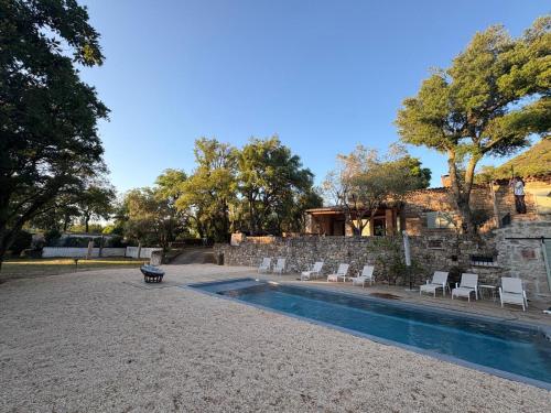 a swimming pool with chairs next to a stone wall at Bastide de Charme en Pierre avec Piscine dans le Golfe de Saint Tropez in Plan-de-la-Tour