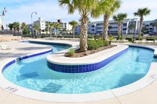 a swimming pool with palm trees in a resort at Tilghman Resort Ocean View Paradise Aw Lazy River & Indoor Outdoor Pools in Myrtle Beach