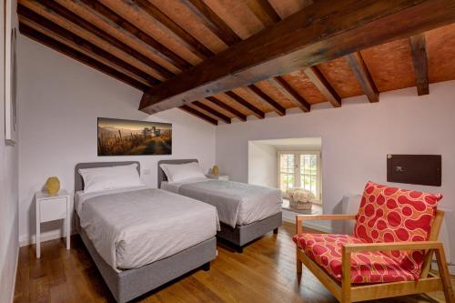 a bedroom with two beds and a chair at Hotel Cortaccia Sanvitale in Sala Baganza