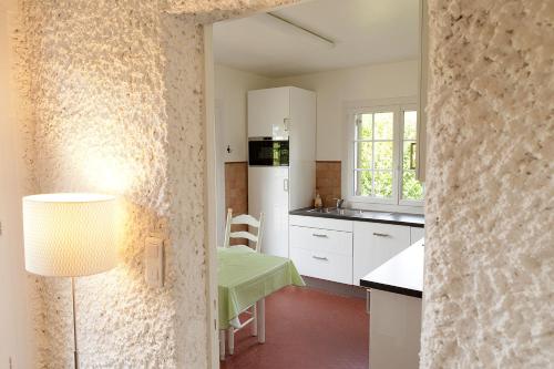 une cuisine avec des placards blancs et une table avec une lampe dans l'établissement Moulin de Vigne, à Corgnac-sur-lʼIsle