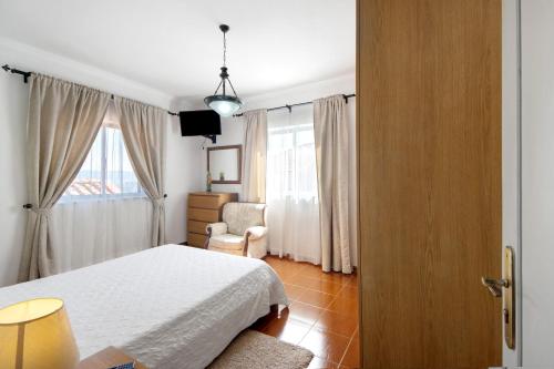 a bedroom with a bed and a chair and a window at Casa Da Jesus in Provesende